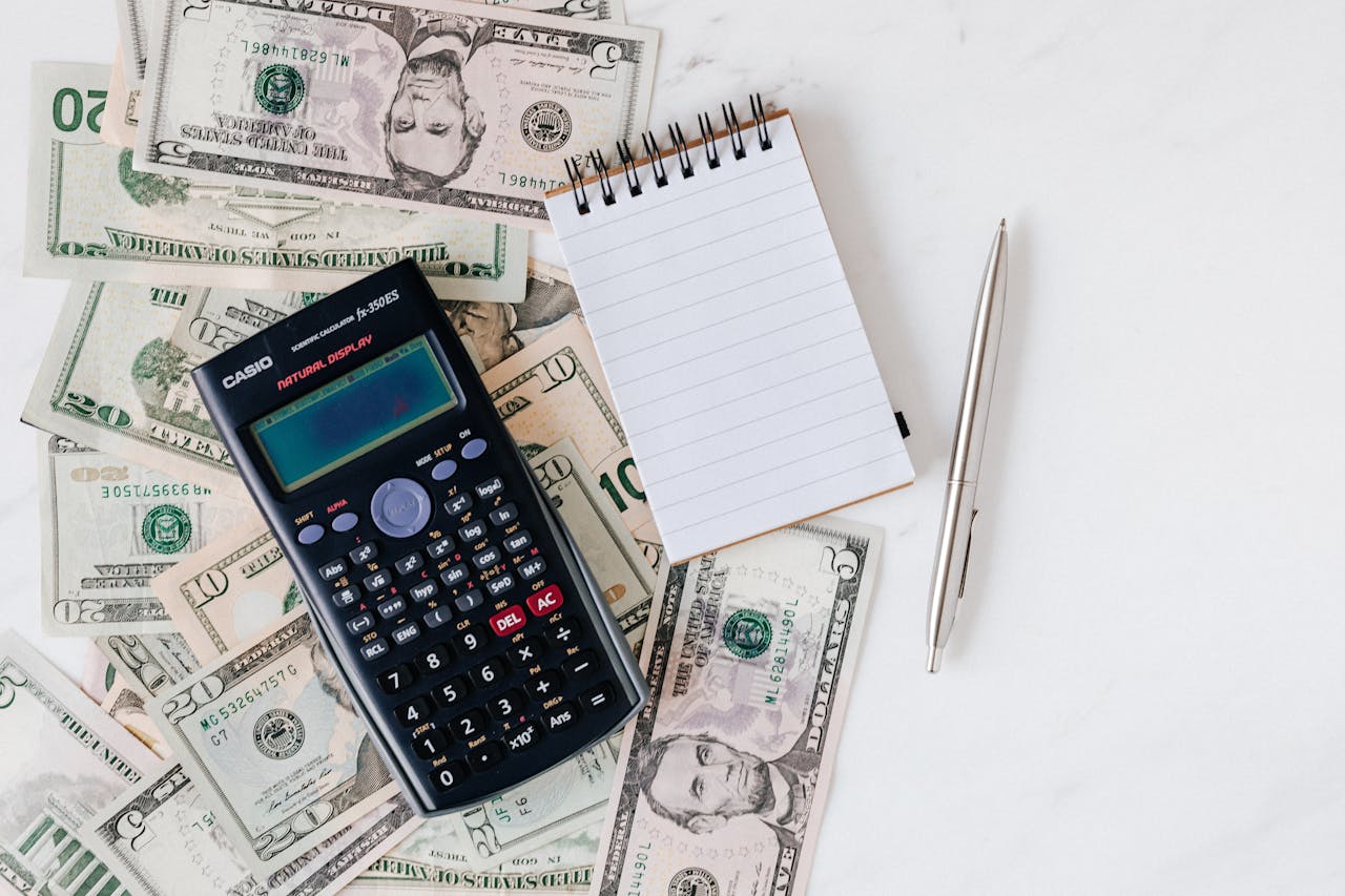 who-we-are Flat lay of US dollar bills with calculator and notebook for budgeting.